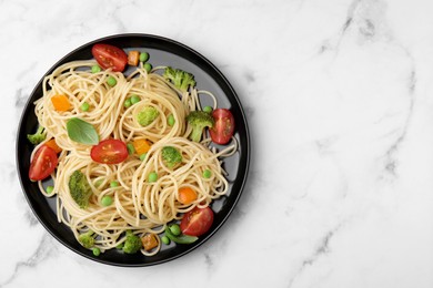 Plate of delicious pasta primavera on white marble table, top view. Space for text