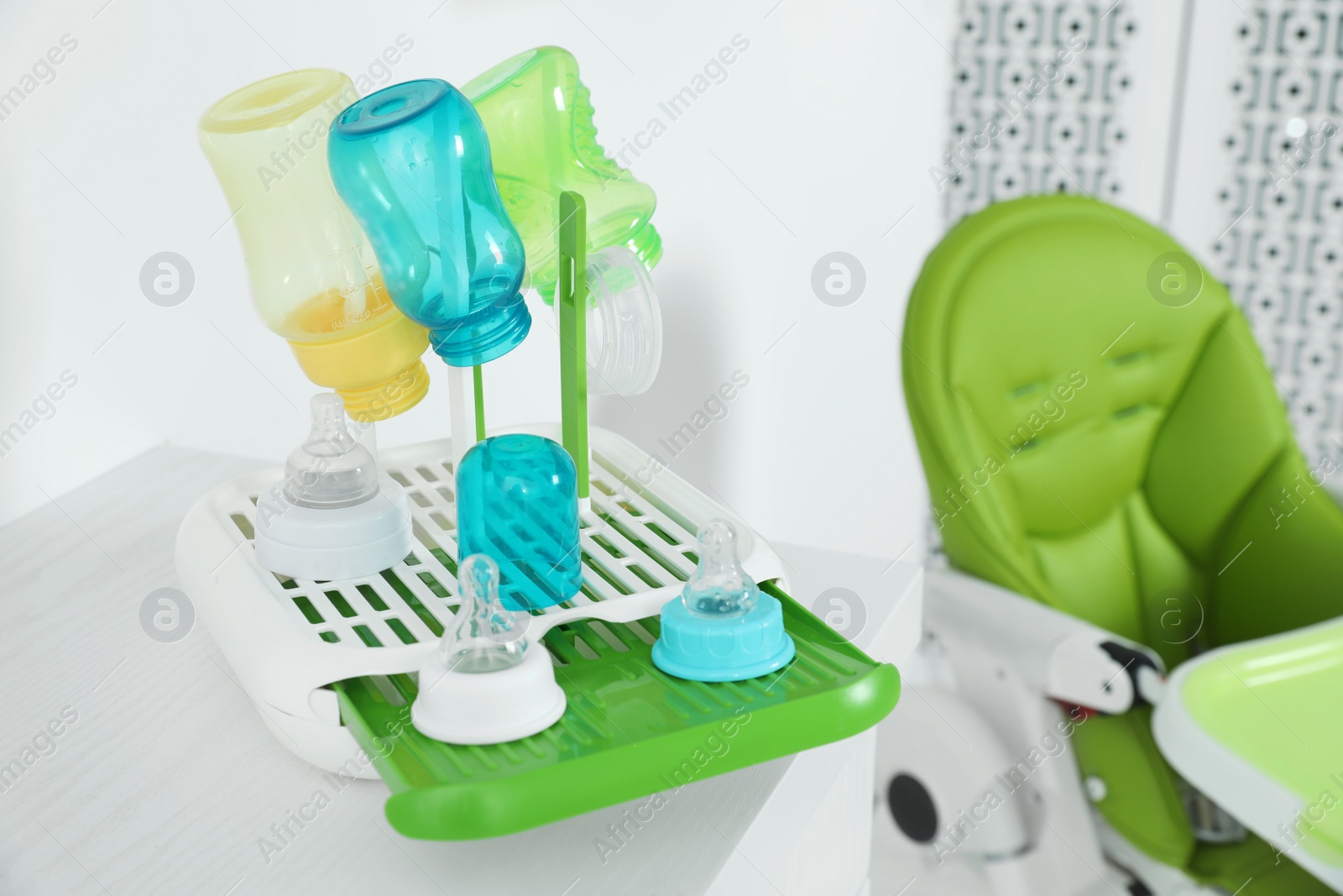 Photo of Dryer with baby bottles and nipples after sterilization on white table indoors