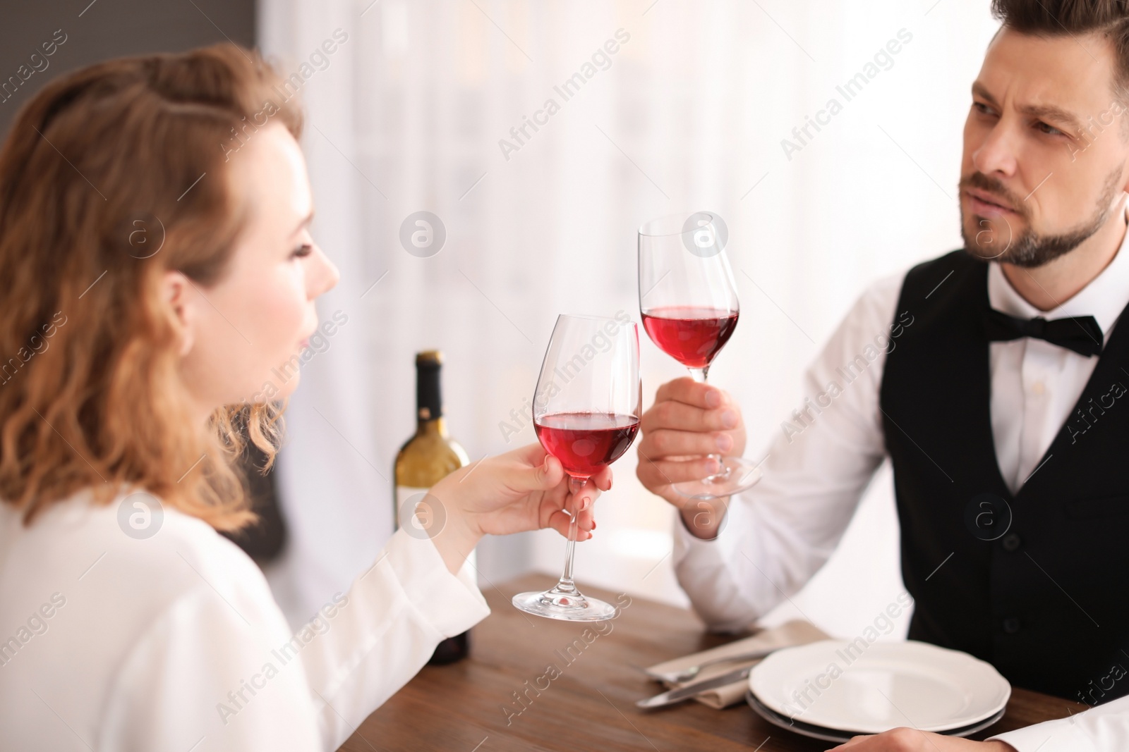 Photo of Young couple with glasses of delicious wine in restaurant