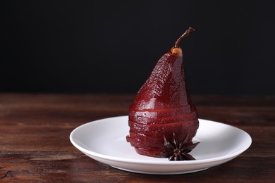 Tasty red wine poached pear and anise on wooden table, closeup. Space for text