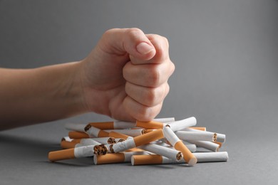 Stop smoking. Woman crushing cigarettes on grey background, closeup