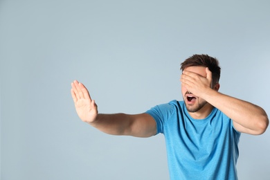 Young man being blinded on grey background