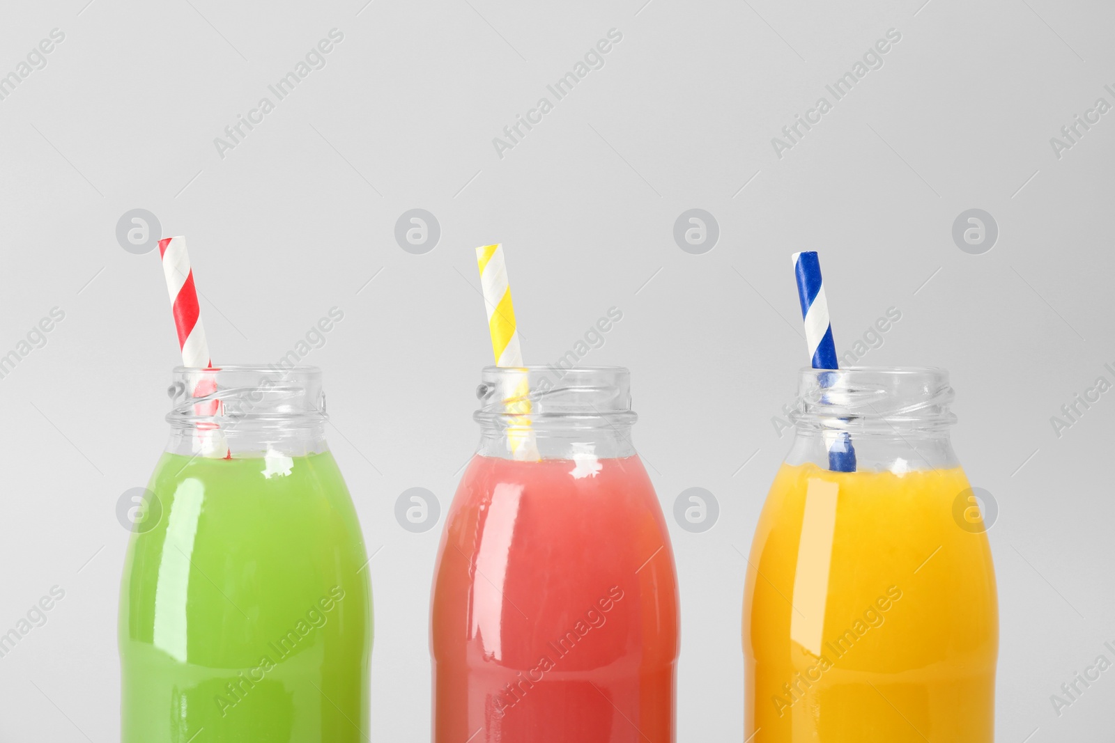 Photo of Bottles with delicious colorful juices on light background