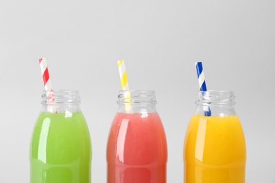 Bottles with delicious colorful juices on light background