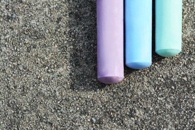 Photo of Colorful chalk sticks on asphalt, flat lay. Space for text