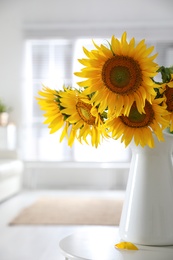 Photo of Bouquet of beautiful sunflowers in vase on table indoors