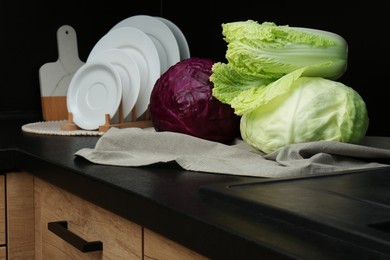 Different types of cabbage on countertop in kitchen