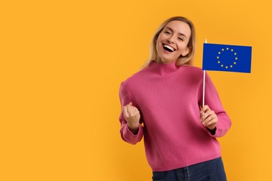 Image of Happy young woman with flag of European Union on yellow background