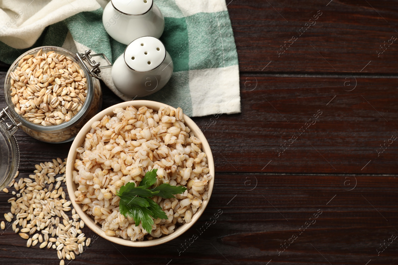 Photo of Delicious pearl barley with parsley served on wooden table, flat lay. space for text