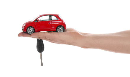 Man holding key and miniature automobile model on white background, closeup. Car buying