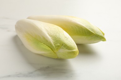 Raw ripe chicories on white marble table, closeup