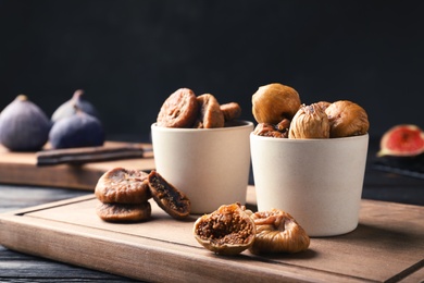 Photo of Bowls with delicious dried figs on wooden board. Organic snack