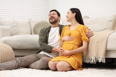 Photo of Happy pregnant woman spending time with her husband at home