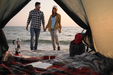 Photo of Couple near sea at sunset, view from camping tent