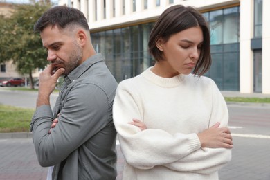 Photo of Man and woman turned away from each other outdoors. Relationship problems