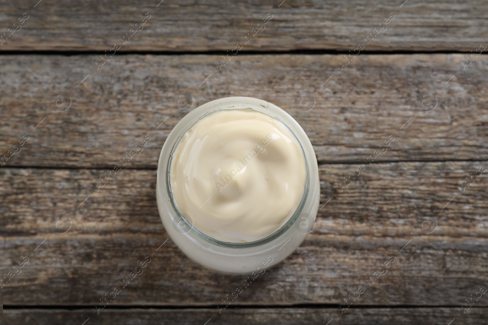 Photo of Fresh mayonnaise sauce in glass jar on wooden table, top view