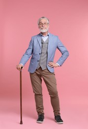 Senior man with walking cane on pink background