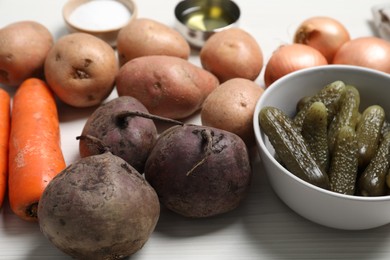 Cooking vinaigrette salad. Many fresh vegetables and pickled cucumbers on white wooden table, closeup