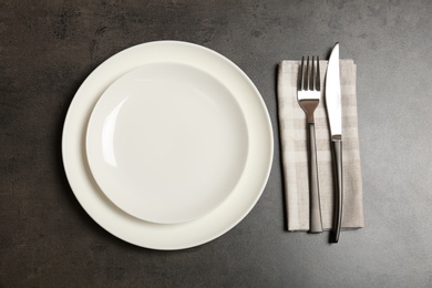 Photo of Empty dishware and cutlery on gray background, top view. Table setting