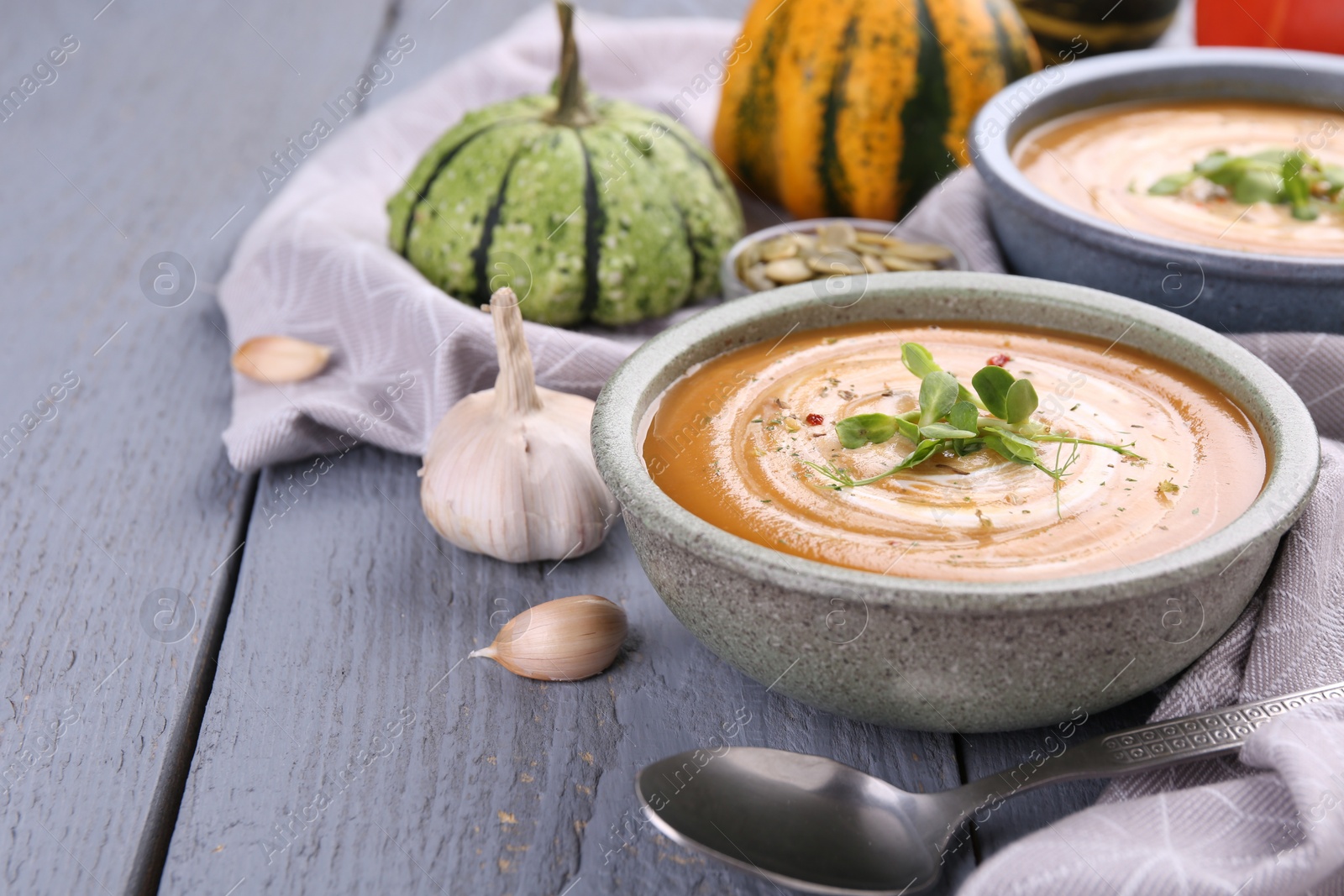 Photo of Delicious pumpkin soup served on gray wooden table. Space for text