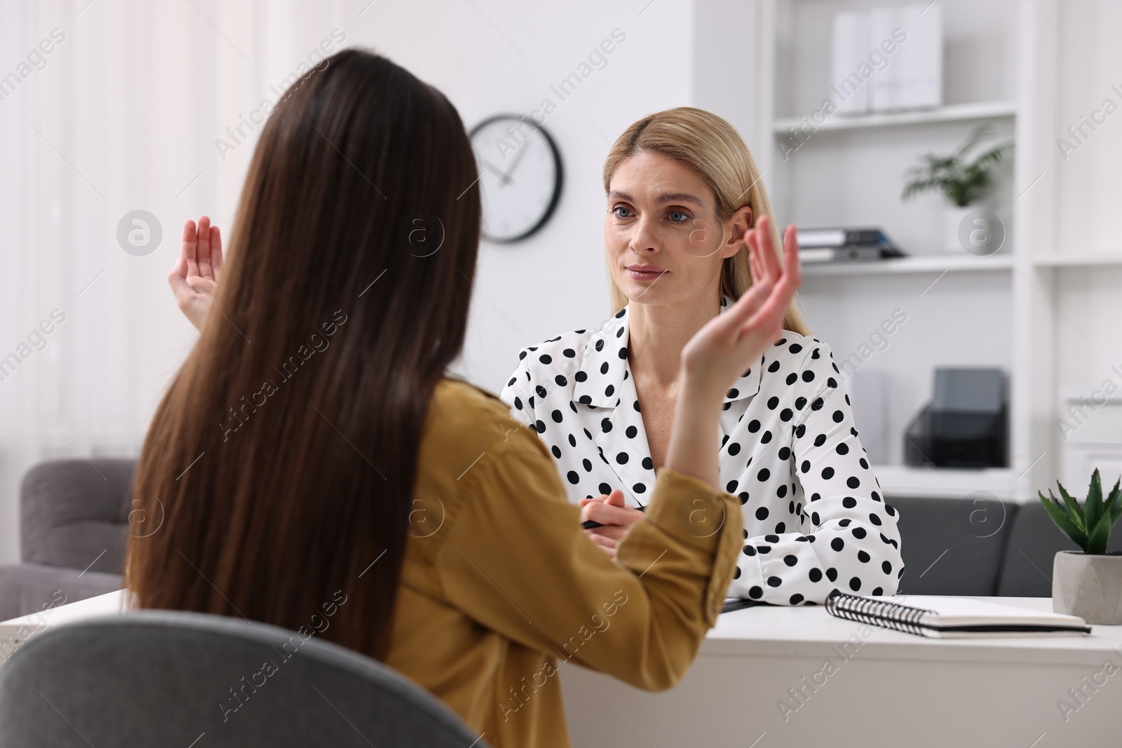 Photo of Psychologist working with teenage girl at table in office