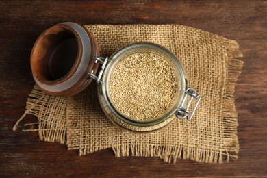 Jar with white quinoa on wooden table, top view