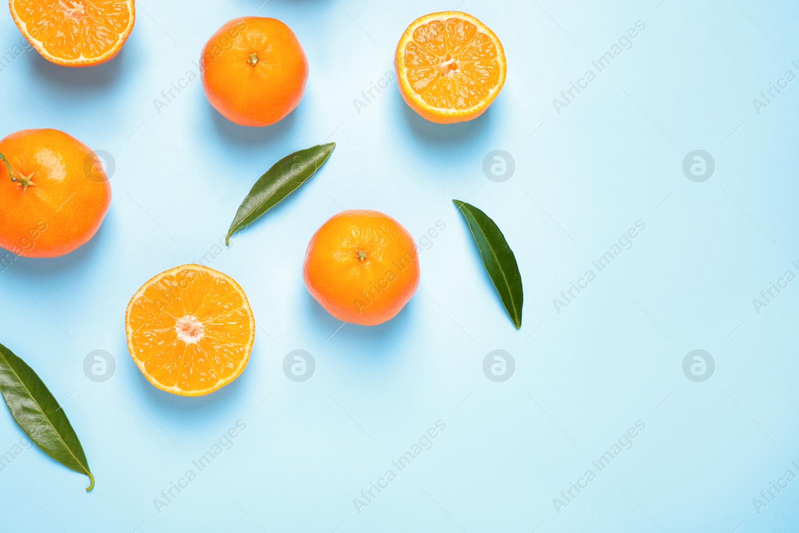 Photo of Flat lay composition with fresh ripe tangerines and leaves on light blue background. Citrus fruit