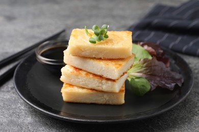 Photo of Delicious turnip cake with herbs served on grey table, closeup