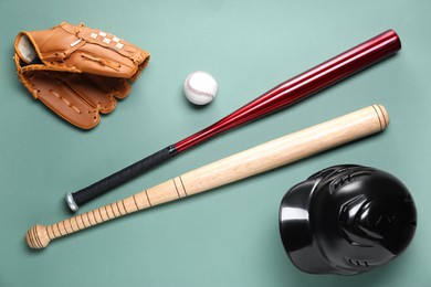 Photo of Baseball glove, bats, ball and batting helmet on pale green background, flat lay