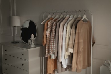 Modern dressing room interior with rack of stylish clothes