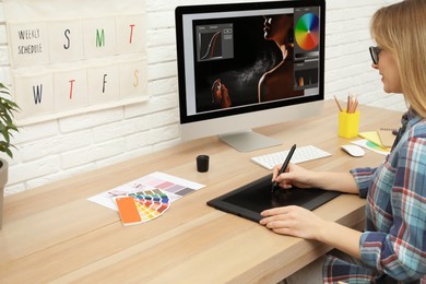 Photo of Professional retoucher working on graphic tablet at desk