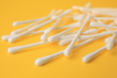 Photo of Many clean cotton buds on yellow background, closeup