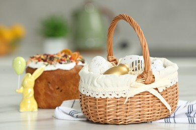 Easter basket with painted eggs near tasty cake on white marble table