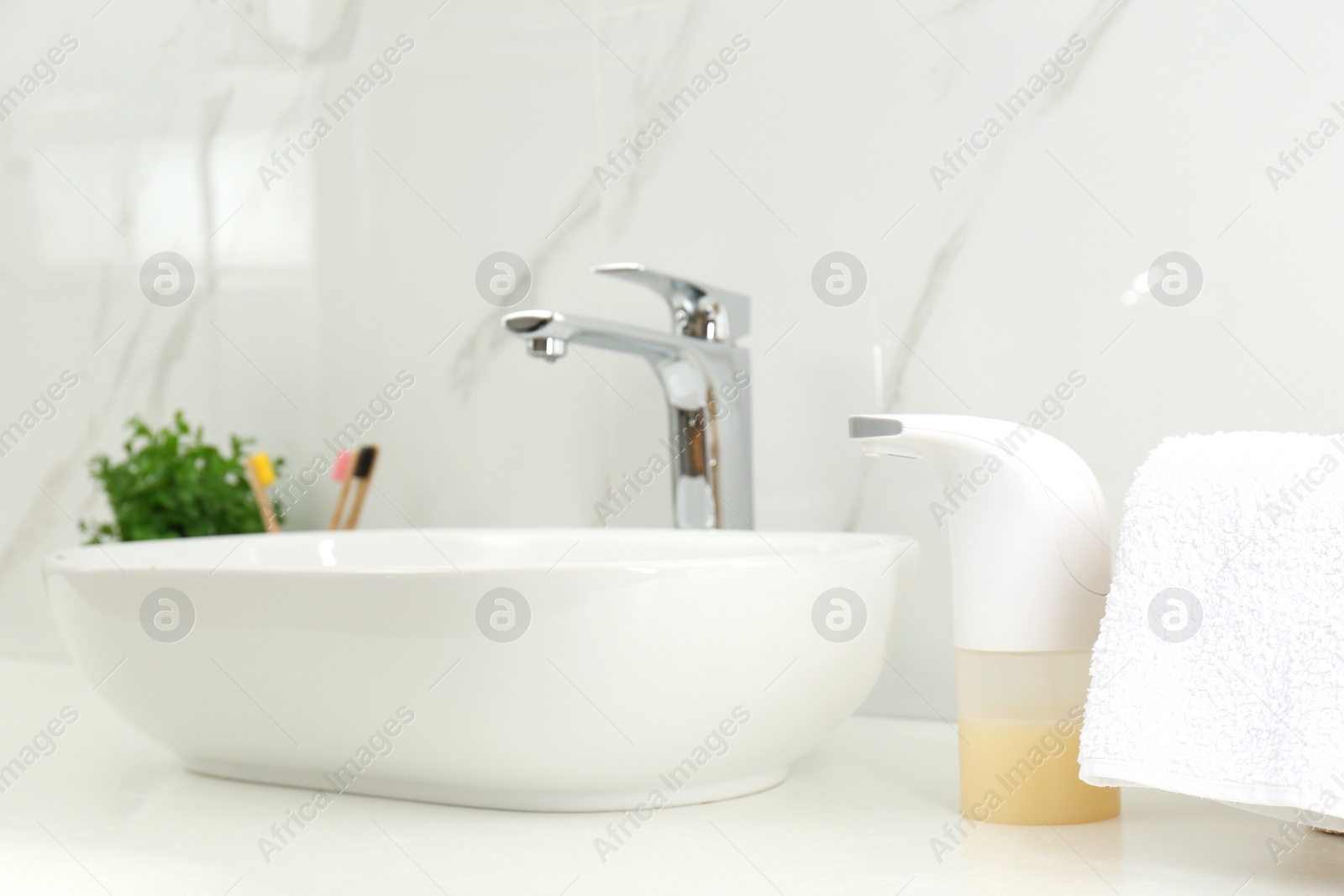 Photo of Modern automatic soap dispenser near sink in bathroom, closeup