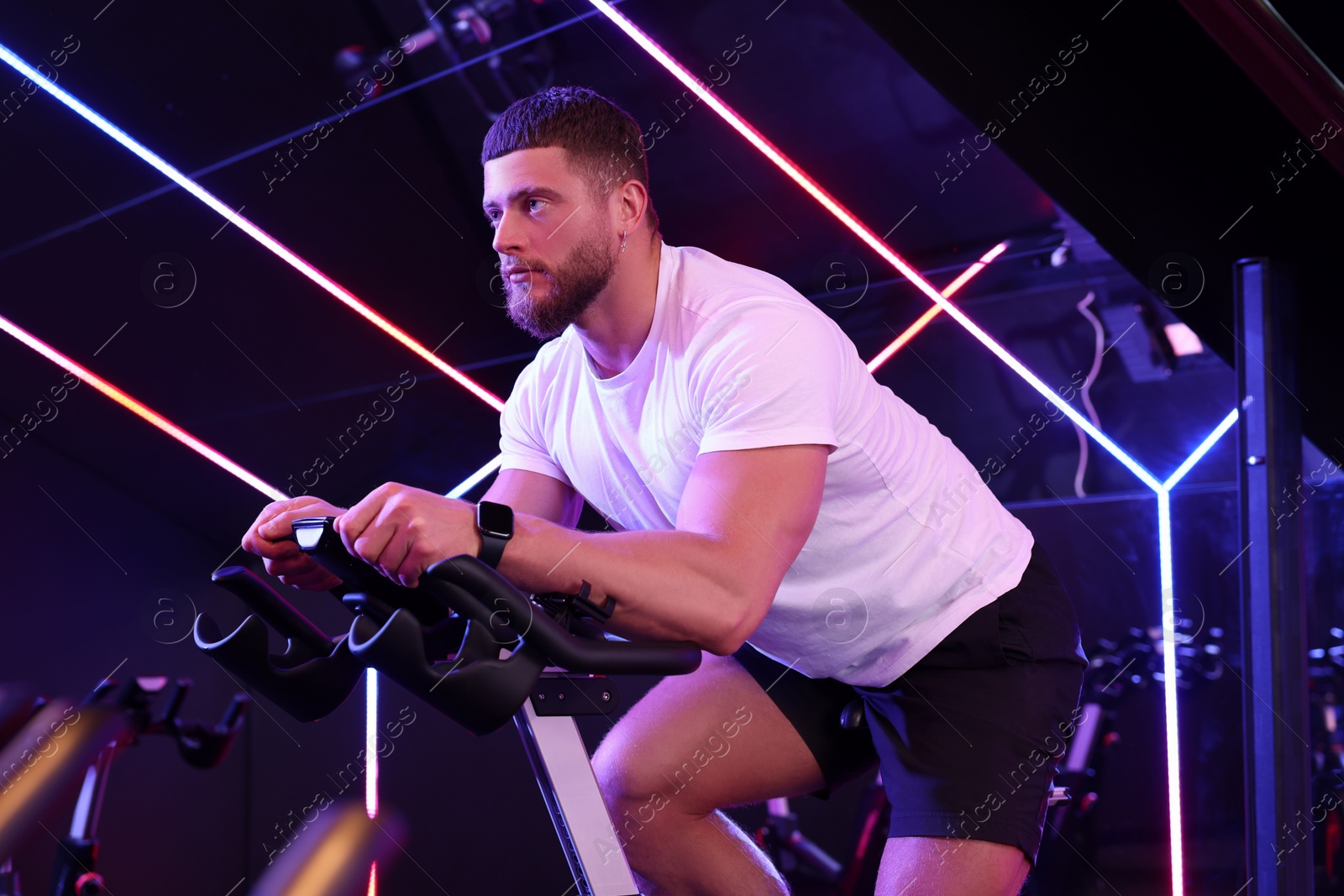 Photo of Young man training on exercise bike in fitness club