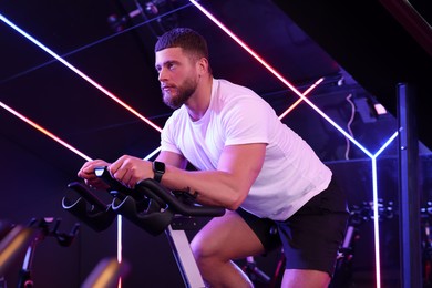 Young man training on exercise bike in fitness club