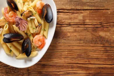 Photo of Delicious pasta with seafood served on wooden table, top view. Space for text