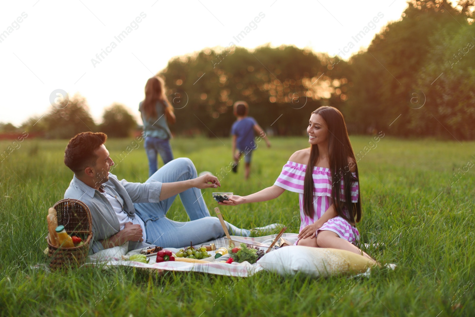 Photo of Happy family having picnic in park at sunset