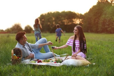 Happy family having picnic in park at sunset