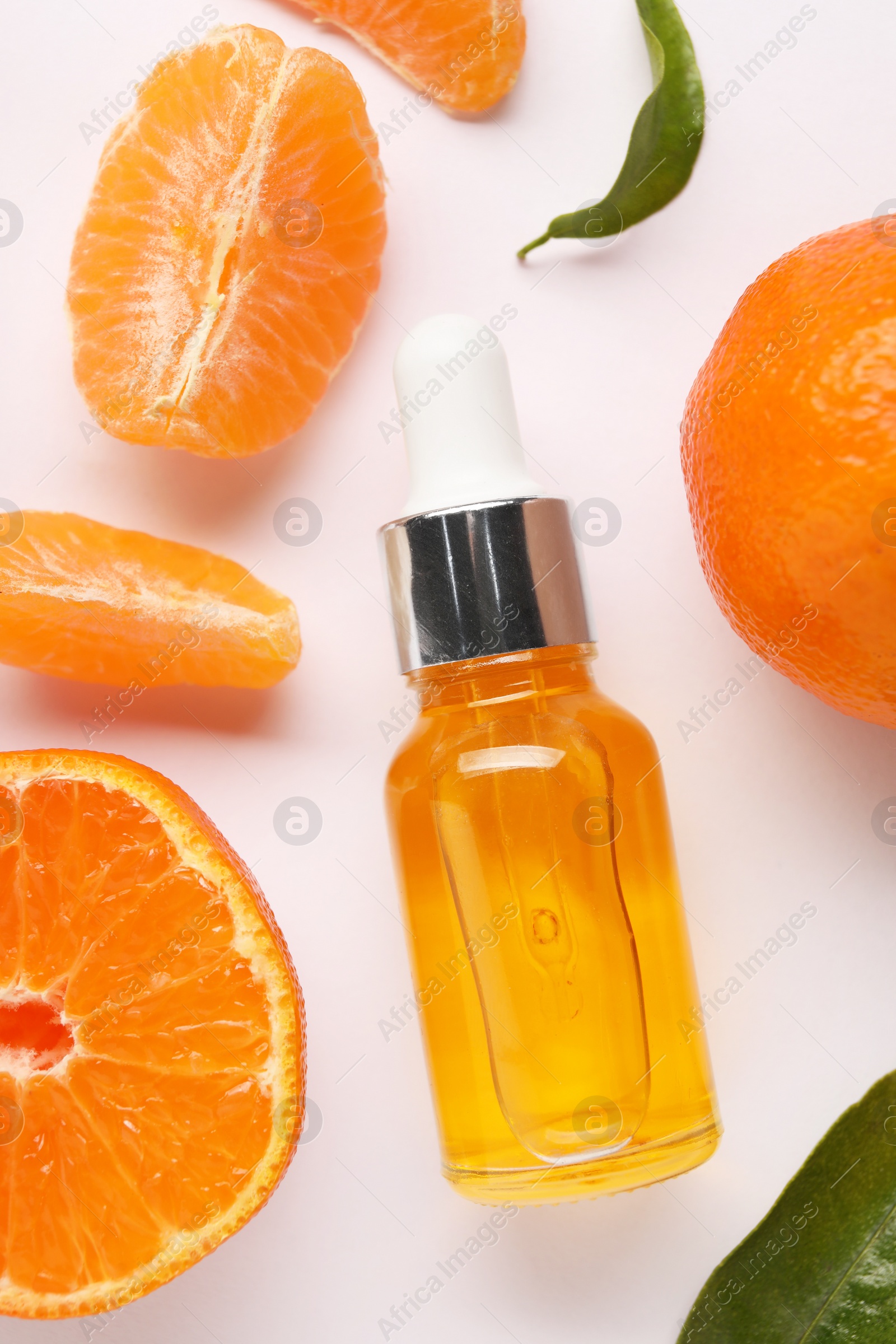 Photo of Aromatic tangerine essential oil in bottle and citrus fruits on white table, flat lay