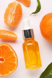 Photo of Aromatic tangerine essential oil in bottle and citrus fruits on white table, flat lay
