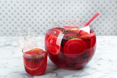 Photo of Glass and bowl of delicious aromatic punch drink on white marble table