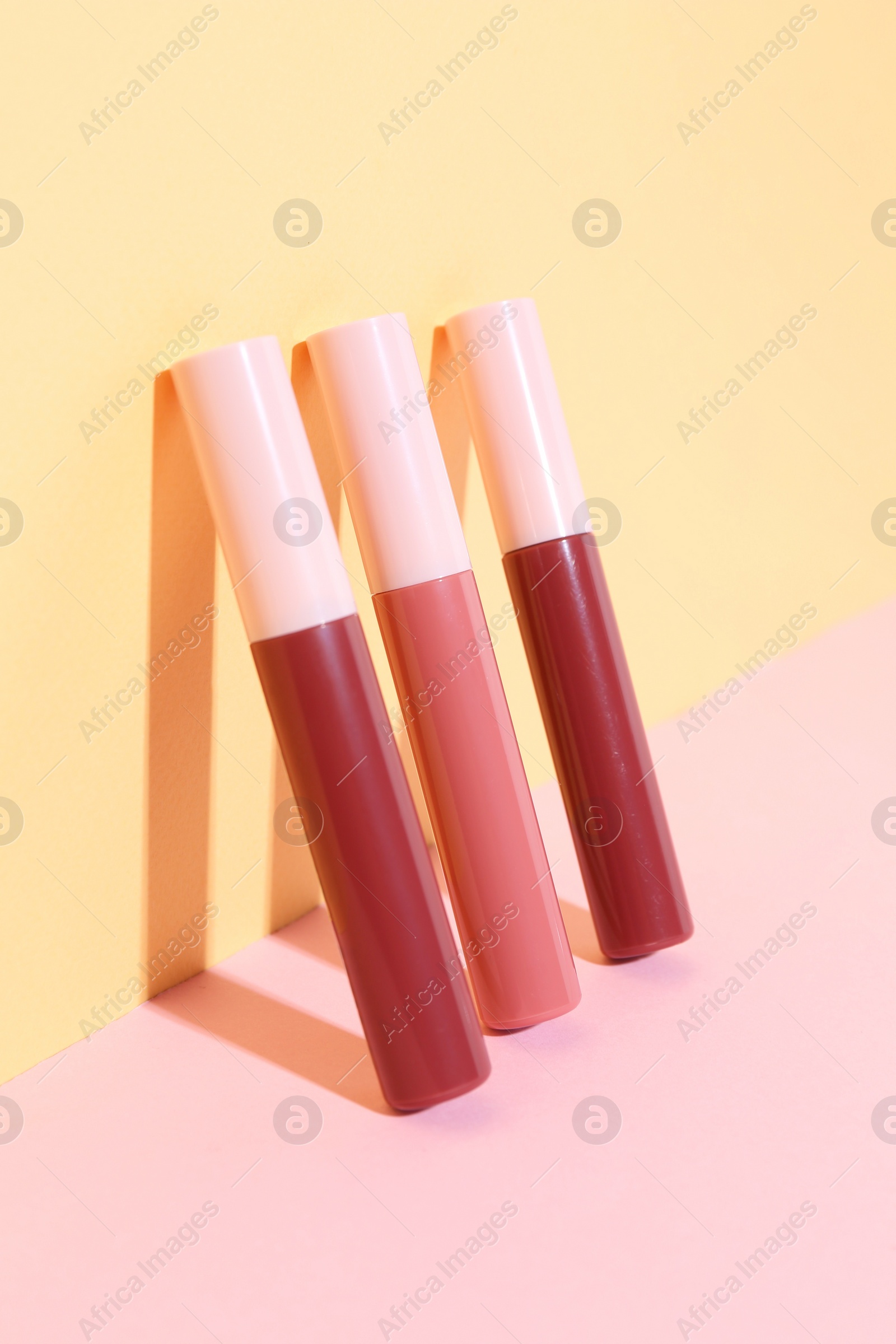 Photo of Many different lip glosses on color background