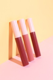 Many different lip glosses on color background