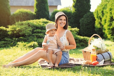 Photo of Mother with her baby daughter having picnic in garden on sunny day