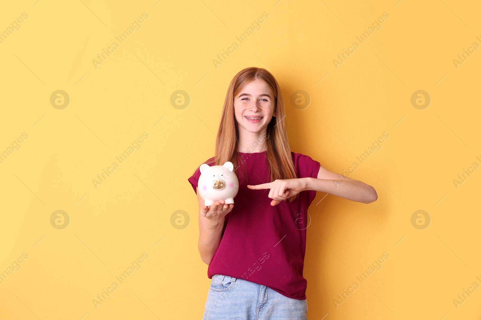 Photo of Teen girl with piggy bank on color background