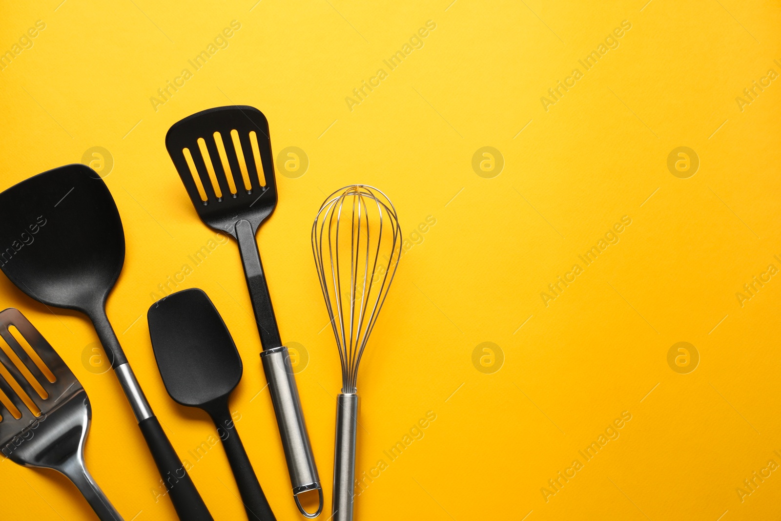 Photo of Different spatulas and whisk on orange background, flat lay. Space for text