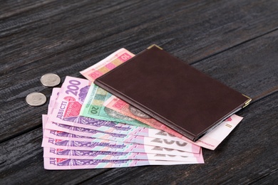 Photo of Pension certificate with Ukrainian money on black wooden background