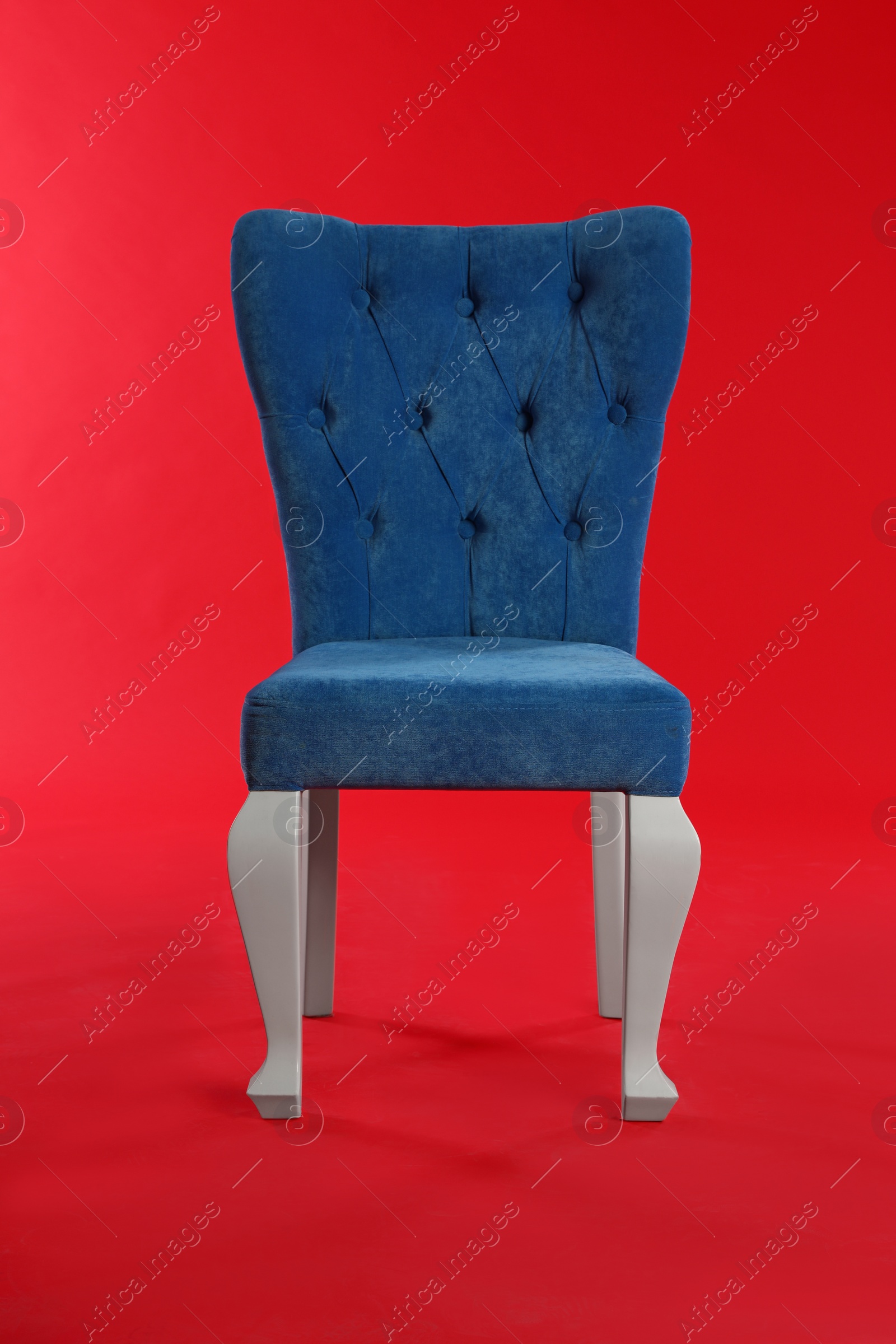 Photo of Stylish blue chair on red background. Element of interior design