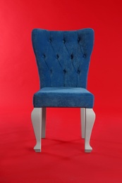 Stylish blue chair on red background. Element of interior design